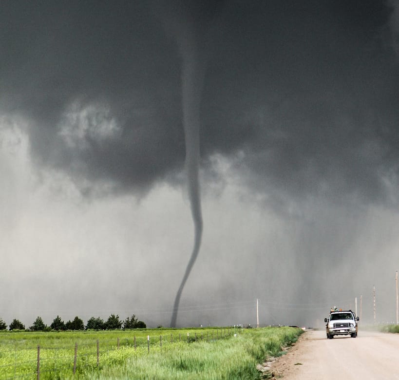 A storm chaser in a truck chasing a tornado.