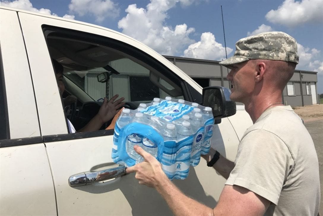A soldier loading water into a truck.